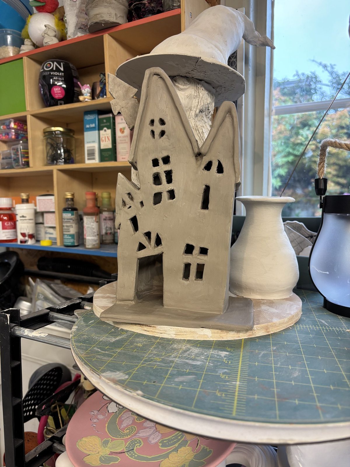 Hands shaping a clay tea light house at Clay Club